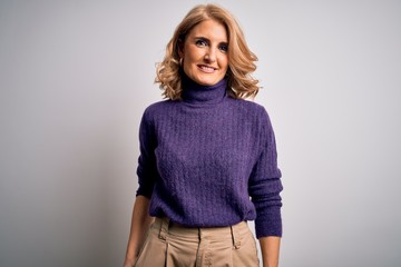 Middle age beautiful blonde woman wearing purple turtleneck sweater over white background with a happy and cool smile on face. Lucky person.