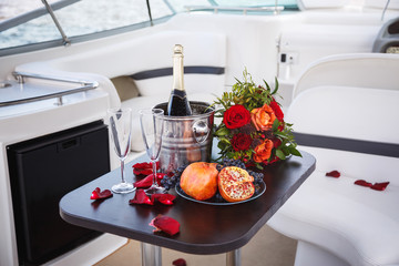 Table on a cruise yacht with cool champagne, flowers and fresh fruit.