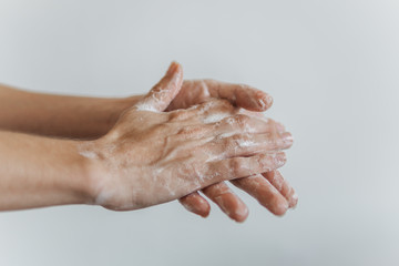 Fototapeta premium Detalhe de mãos femininas com espuma de sabonete. Lavar as mãos para combater o coronavírus.