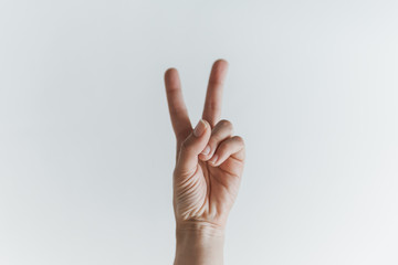 Mão de mulher branca fazendo o número 2 ou símbolo de vitória 
