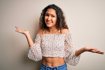 Young beautiful woman with curly hair wearing casual t-shirt standing over white background...