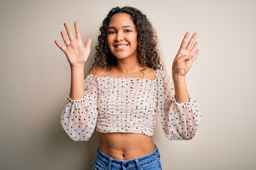 Young beautiful woman with curly hair wearing casual t-shirt standing over white background showing...