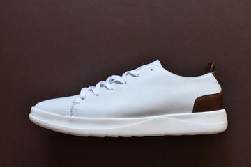 Hipster white sneakers on dark brown background