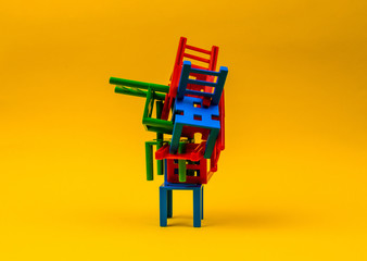 Plastic chairs stand on top of each other on a yellow background. The concept of solving complex problems, confusing situation, problems in business.