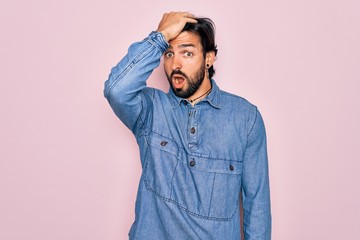 Fototapeta premium Young handsome hispanic bohemian man wearing hippie style over pink background surprised with hand on head for mistake, remember error. Forgot, bad memory concept.
