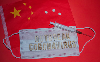 OUTBREAK CORONAVIRUS is wording on a protective medical mask. China's flag, tablets and syringe on...