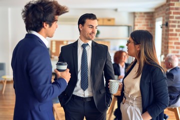 Young beautiful group of business workers smiling happy and confident, Standing with smile on face drinking coffee and speaking at the office