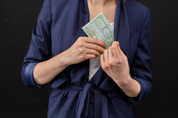 Girl in a jacket removes euro bills in his pocket on a black background.