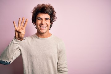 Young handsome man wearing casual t-shirt standing over isolated pink background showing and pointing up with fingers number four while smiling confident and happy.