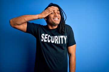 Young african american afro safeguard man with dreadlocks wearing security uniform stressed with...