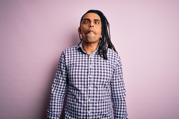 Fototapeta premium Young handsome african american afro man with dreadlocks wearing casual shirt making fish face with lips, crazy and comical gesture. Funny expression.
