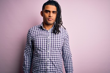 Young handsome african american afro man with dreadlocks wearing casual shirt Relaxed with serious expression on face. Simple and natural looking at the camera.