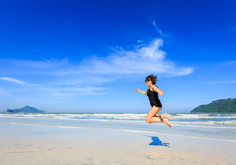 Woman jumping on sand beach on beautiful sunny day
