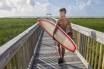 Young teen on boardwalk with surfboard