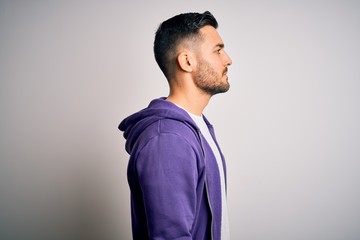 Young handsome man wearing purple sweatshirt standing over isolated white background looking to...
