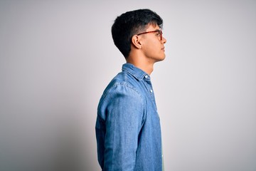 Young handsome man wearing casual shirt and glasses over isolated white background looking to side,...