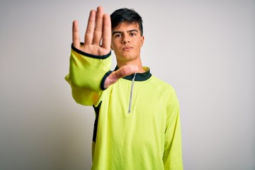 Young handsome sportsman doing sport wearing sportswear over isolated white background doing stop...