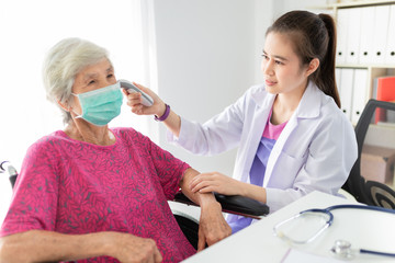 Fototapeta premium Asian doctor talk with old female patient about disease symptom, doctor use infrared thermoscan measure temperature to patient, elderly health check up, fever screening