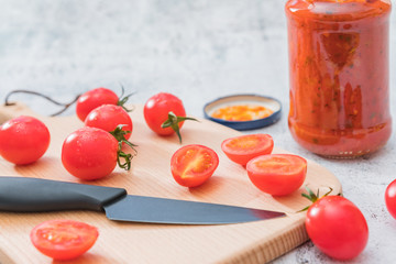 Cherry tomatoes and a spoonful of ketchup on a cutting board
