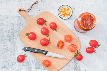 Naklejka na ściany i meble Cherry tomatoes and a spoonful of ketchup on a cutting board