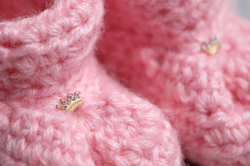 Two earrings in the form of a crown in small pink booties.