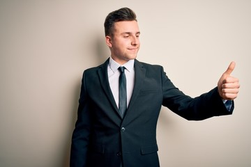 Young handsome business man wearing elegant suit and tie over isolated background Looking proud, smiling doing thumbs up gesture to the side