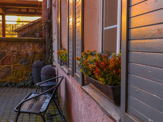 Ławka przed domem, kwiaty w oknach o zachodzie słońca © Michal