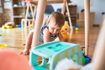 Adorable toddler playing around lots of toys at kindergarten