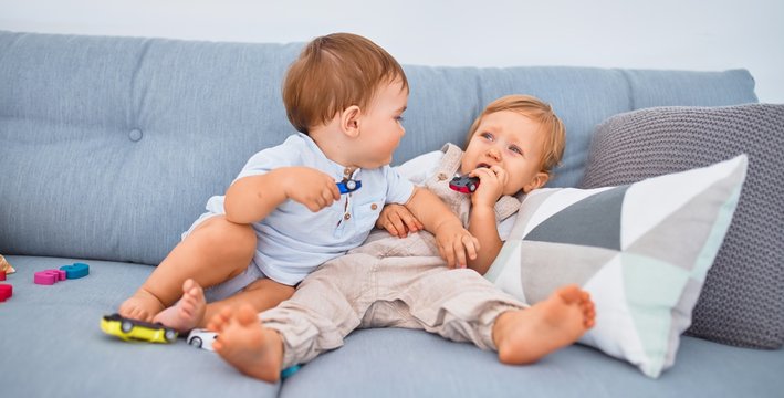 Beautiful toddlers sitting on the sofa playing with toys at home
