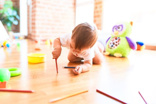 Adorable toddler crawling  around lots of toys at kindergarten