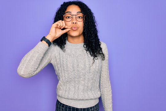 Young african american woman wearing casual sweater and glasses over purple background mouth and lips shut as zip with fingers. Secret and silent, taboo talking