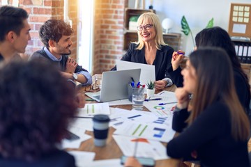 Group of business workers smiling happy and confident. Working together with smile on face  using laptop and speaking at the office