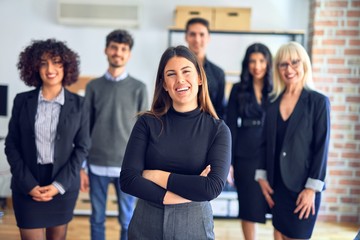 Group of business workers smiling happy and confident. Posing together with smile on face looking at the camera, young beautiful woman with crossed arms at the office