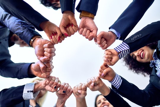 Group of business workers standing bumping fists at the office