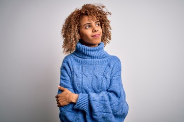 Young beautiful african american woman wearing turtleneck sweater over white background looking to the side with arms crossed convinced and confident