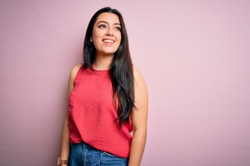 Young brunette woman wearing casual summer shirt over pink isolated background looking away to side with smile on face, natural expression. Laughing confident.