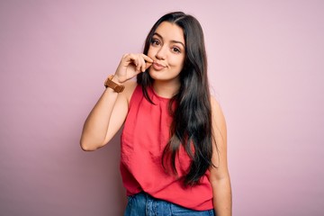 Young brunette woman wearing casual summer shirt over pink isolated background mouth and lips shut as zip with fingers. Secret and silent, taboo talking