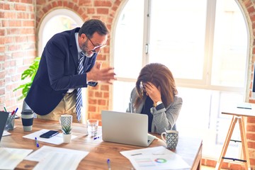 Two middle age business workers working together. Man bullying woman at the office