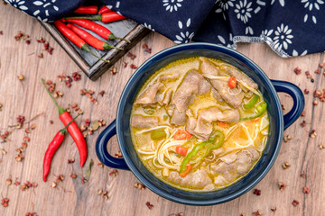 A bowl of beef in Flammulina mushroom and sour soup on the wooden table
