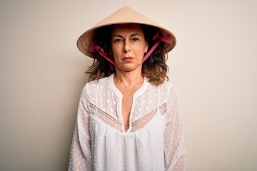 Middle age brunette woman wearing asian traditional conical hat over white background depressed and worry for distress, crying angry and afraid. Sad expression.