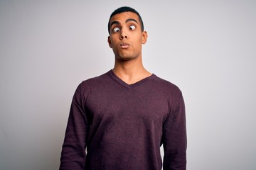 Young handsome african american man wearing casual sweater over white background making fish face with lips, crazy and comical gesture. Funny expression.