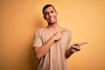 Young handsome african american man wearing casual t-shirt standing over yellow background Pointing...