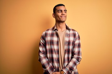 Young handsome african american man wearing casual shirt standing over yellow background smiling...