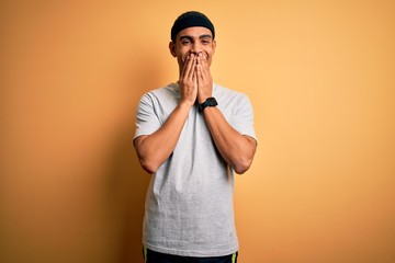 Handsome african american sportsman doing sport wearing sportswear over yellow background laughing...