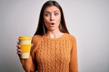 Young beautiful woman with blue eyes drinking cup of takeaway coffee over isolated background scared in shock with a surprise face, afraid and excited with fear expression