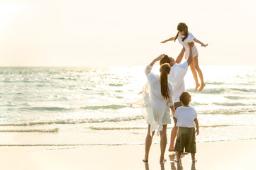 Happy Young Asian happy family parents with child walking and having fun together on the beach at...