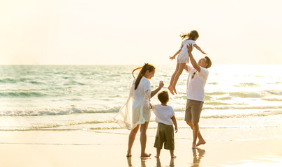 Happy Young Asian happy family parents with child walking and having fun together on the beach at...