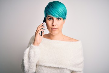 Young woman with blue fashion hair having a conversation talking on smartphone with a confident expression on smart face thinking serious