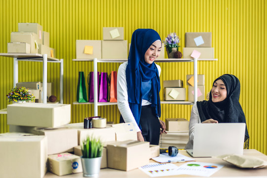 Portrait Of Smiling Beautiful Two Muslim Owner Asian Woman Freelancer Sme Business Online Shopping Working On Laptop Computer With Parcel Box On Table At Home - Business Online Shipping And Delivery