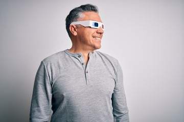 Middle age handsome grey-haired man using 3d glasses over isolated white background looking away to side with smile on face, natural expression. Laughing confident.